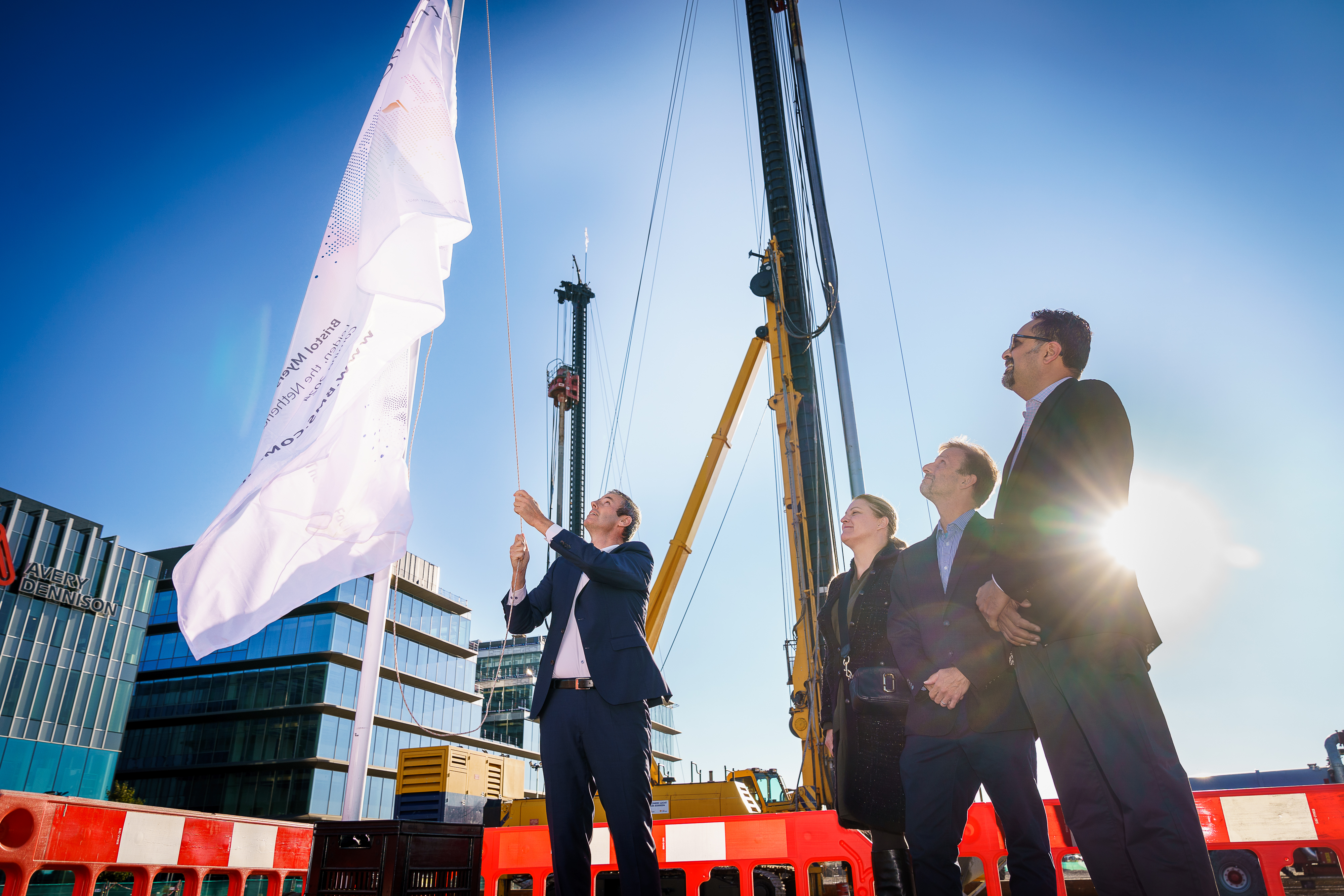 Three workers in helmets standing in front of building site