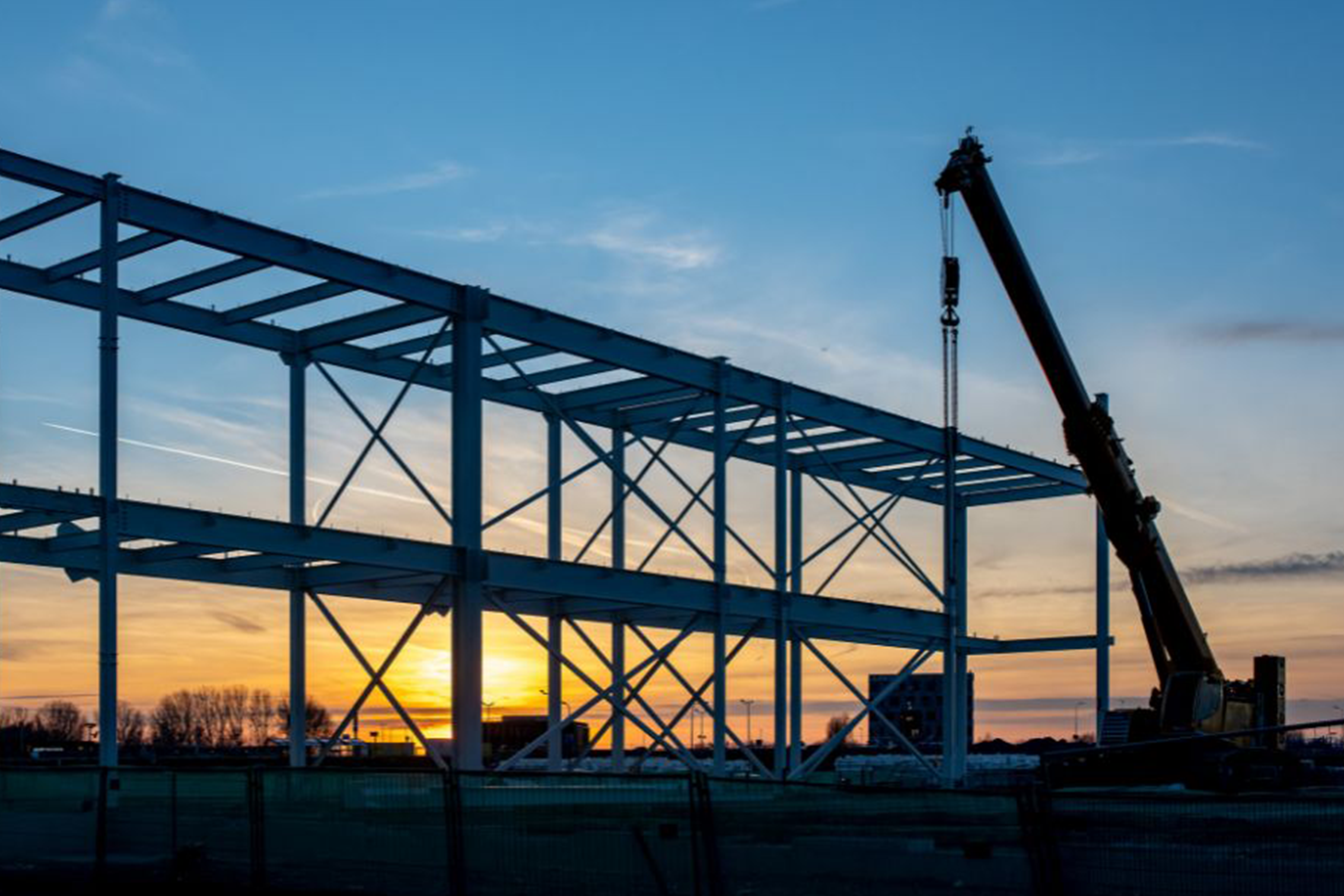 Three workers in helmets standing in front of building site