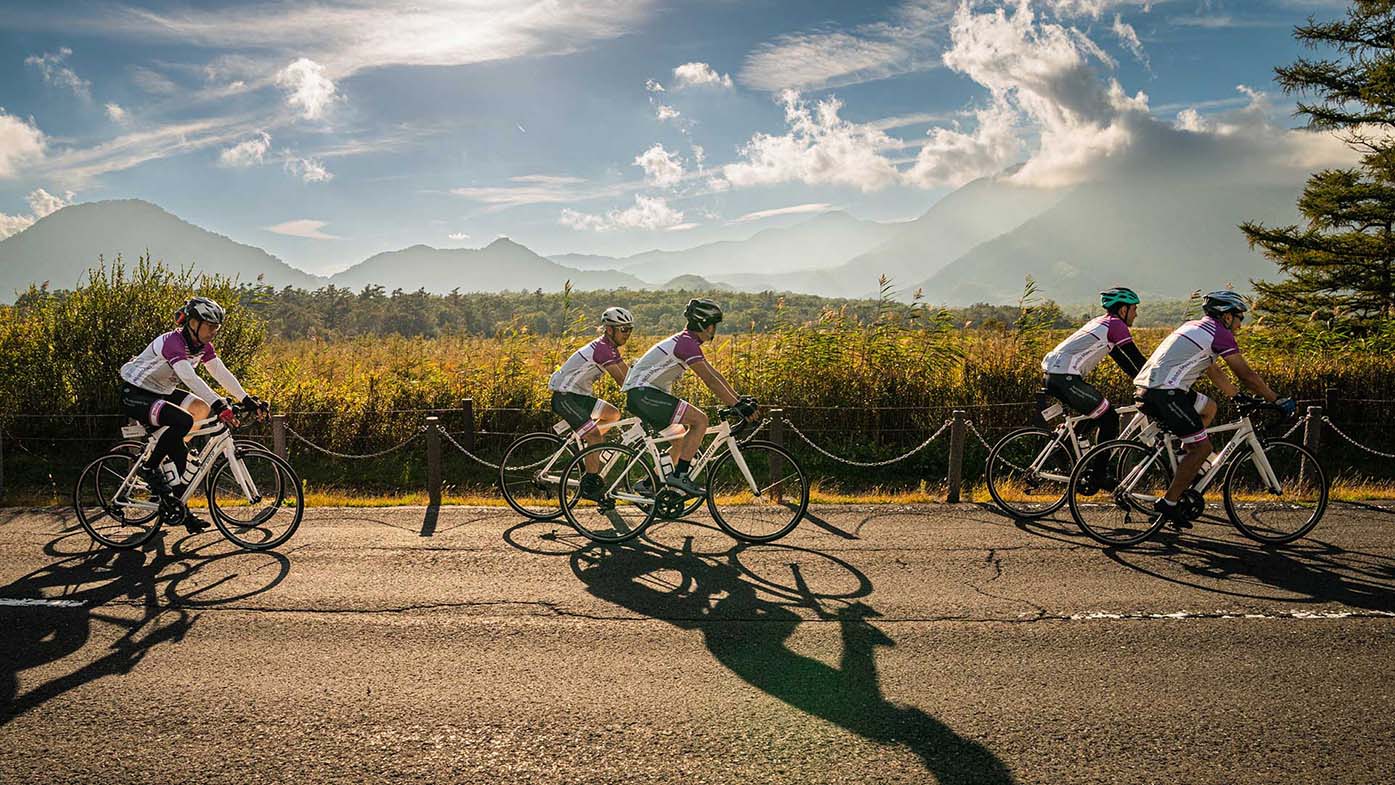 Giovanni Caforio shaking hands with a cyclist