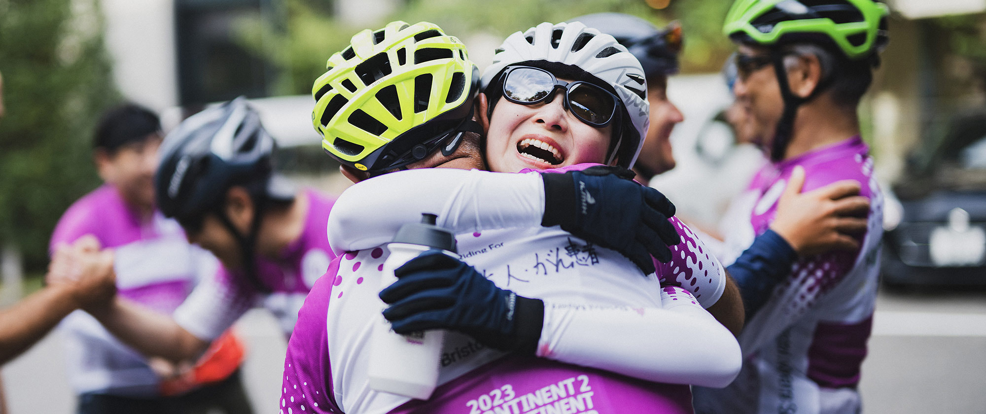 Two bike race riders sharing an emotional embrace