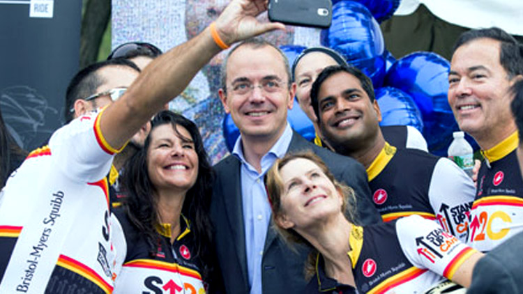 Giovanni Caforio takes a group photo with cyclists