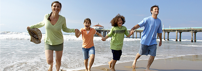 Familie ținându-se de mână și alergând pe plajă