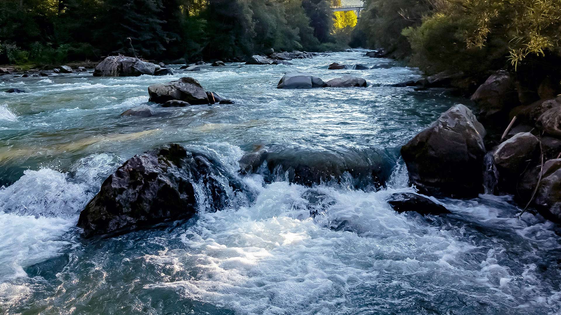 A woman hiking in nature near a stream and mountain range